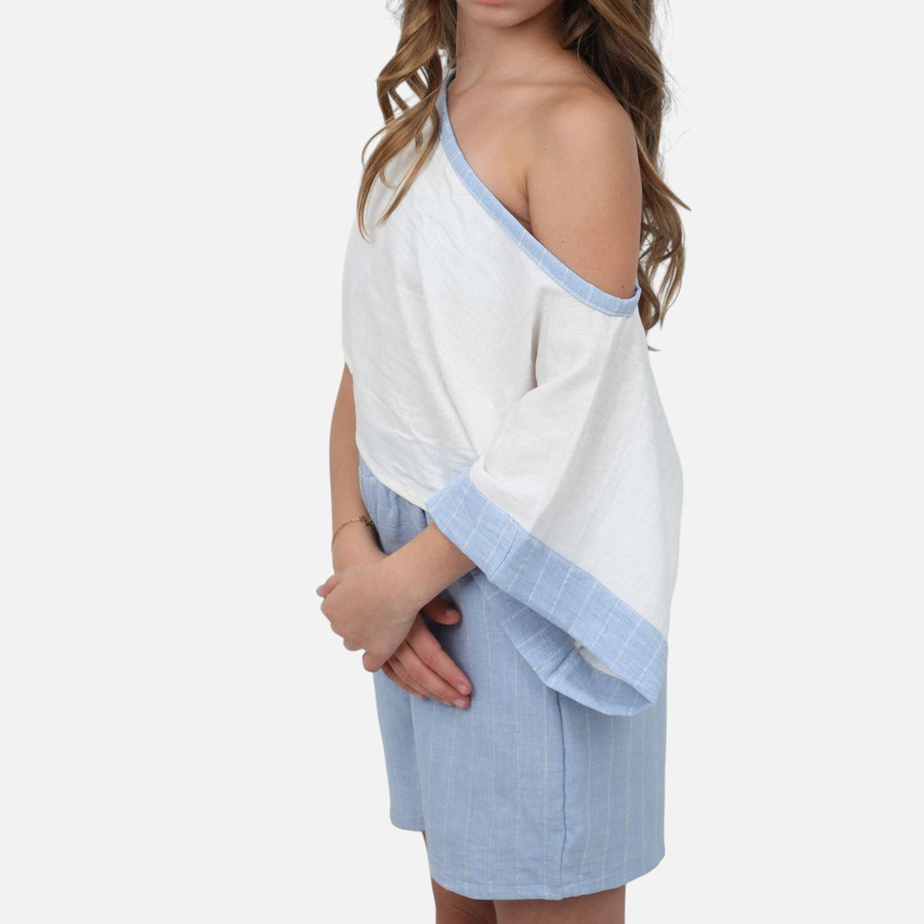 Nounami off-shoulder white top with blue trim and matching pinstripe shorts on a model, side view.