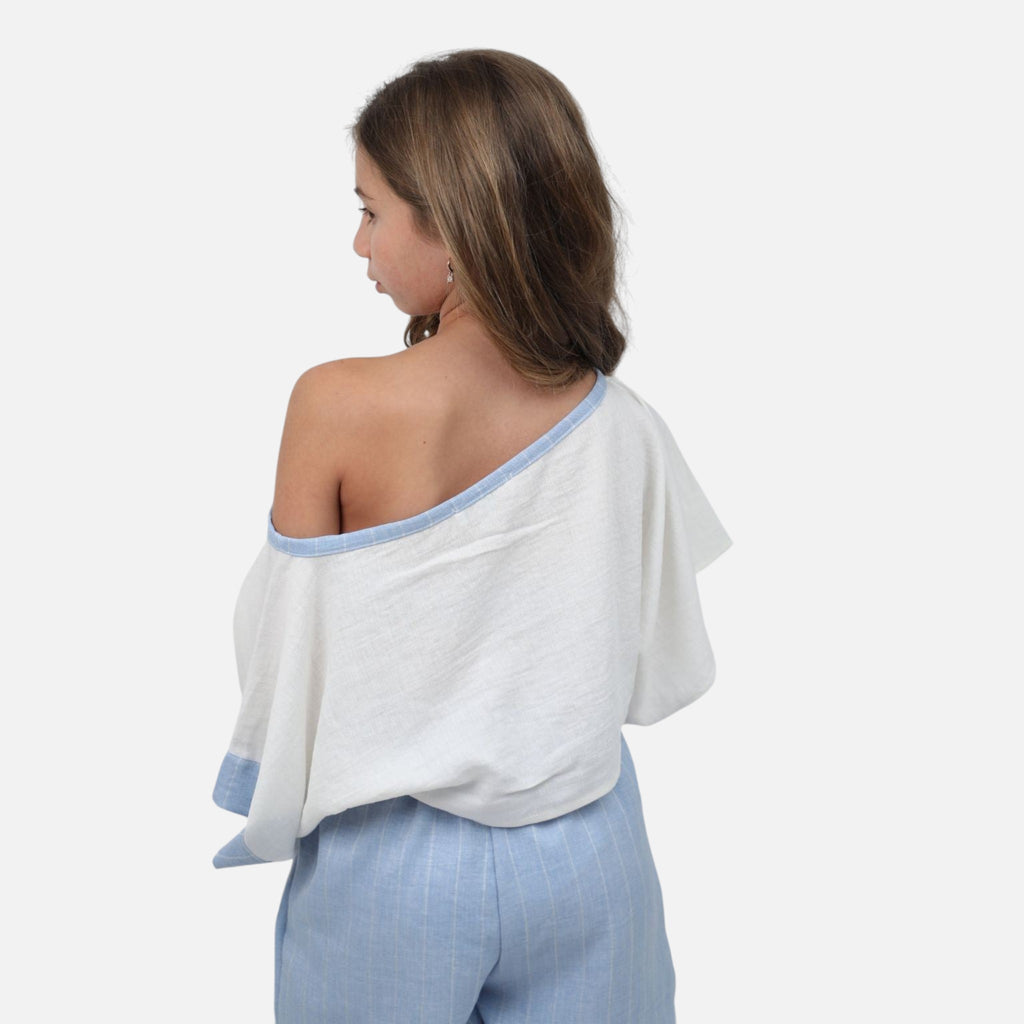 Nounami off-shoulder white top with blue trim and matching pinstripe shorts worn by a girl, back view